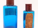 two blue bottles with wooden lids on a white surface
