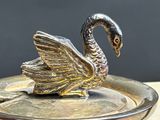 a silver plate with a swan on it on a table