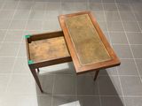 une petite table avec un tiroir, posée sur un sol carrelé