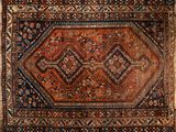 un vieux tapis persan aux motifs géométriques posé sur un parquet