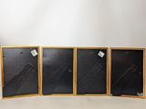 three black and gold framed pictures with tags on them on a white surface
