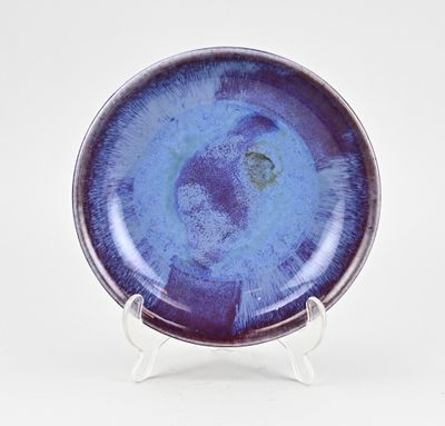assiette violette et bleue posée sur un support, sur fond blanc