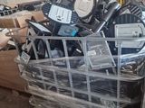 a pile of electronic equipment in a cart in a warehouse