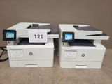 two hp laser printers are sitting side by side on a table