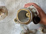 a person that is holding a tea pot on a table