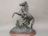 statue représentant un cheval avec un cavalier sur le dos, posée sur un socle en bois