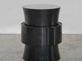 une table d'appoint noire avec un piètement circulaire et un plateau rond