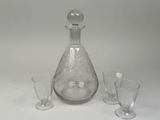 a glass decanter and four wine glasses on a table