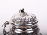 a silver tea pot sitting on a table with a spoon