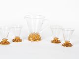 trois verres transparents et un pichet posés les uns à côté des autres sur une surface blanche