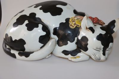 une figurine de vache noire et blanche couchée sur une table