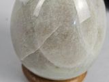 a white marble ball on a wooden stand next to a black and white cat