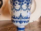 a blue and white vase sitting on a table next to a plate
