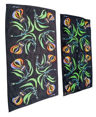 deux serviettes noires ornées de motifs floraux colorés, accrochées à un mur