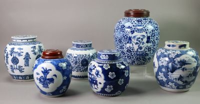 several blue and white vases with lids are lined up on a table