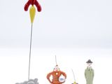 three figurines of a man and a woman standing next to a rocket