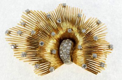 a gold brooch with diamonds on it on a white surface
