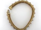 a gold bracelet with spikes on a white background