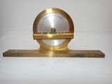 une horloge ancienne en laiton posée sur une étagère en bois, sur fond blanc