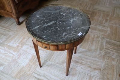 une table avec un plateau en marbre posée sur un piètement en bois, dans une pièce