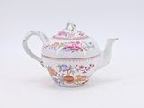 a white teapot with a pink and blue design on it