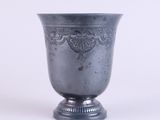 a silver vase sitting on a pedestal on a white surface
