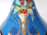 a blue vase with flowers on it sitting on a stand
