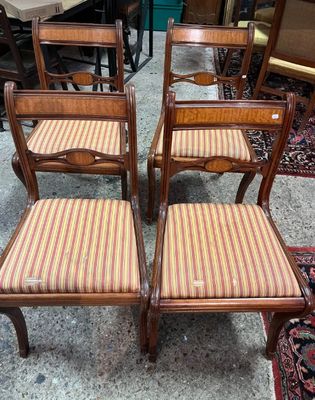 Quatre chaises en bois, dont les assises sont recouvertes d'un tissu rayé, se trouvent dans une pièce