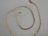 a gold necklace and bracelet set on a white surface