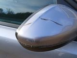 reflection of a car ' s side mirror on the side of a silver car