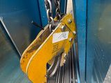 une grue jaune suspendue au flanc d'un immeuble bleu