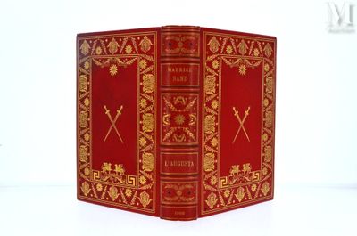 un livre rouge orné de motifs dorés, posé sur une surface blanche