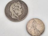 an old silver coin and a silver dime on a white surface