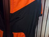 an orange and black jacket hanging on a wooden wall next to a pair of shoes