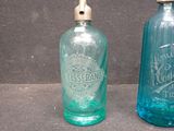 two blue glass bottles sitting next to each other on a table