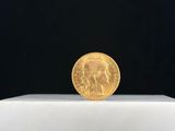 un gros plan d'une pièce d'or posée sur une surface blanche