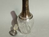 a small glass bottle with a silver lid next to a silver spoon