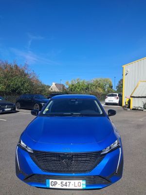 une voiture bleue garée dans un parking à côté d'un bâtiment