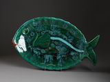 a green plate with a fish on it sitting on a table