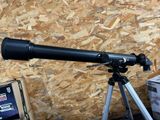 a black telescope on a tripod next to a box of boxes