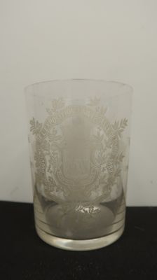 a glass with a crest on it on a table
