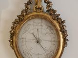a gold clock hanging on the wall with a clock on it