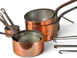 a lot of copper pots and pans sitting on a table