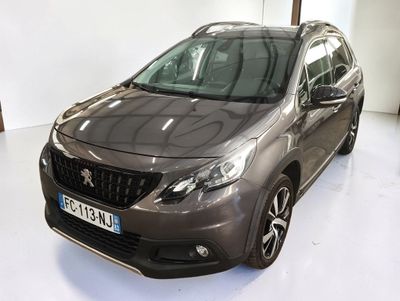 La voiture grise est garée dans une pièce blanche au sol blanc.