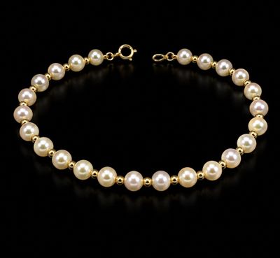 a gold bracelet with pearls on a black background