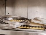 Plusieurs casseroles remplies d'aliments sont empilées sur une étagère dans une cuisine.