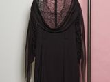 une robe noire suspendue à un cintre devant un mur rose