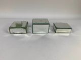 three small glass boxes sitting on top of a white surface