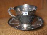 une tasse et une soucoupe en argent posées sur une table en bois