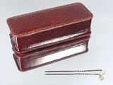 une petite boîte rouge sur laquelle est représentée une paire de ciseaux
